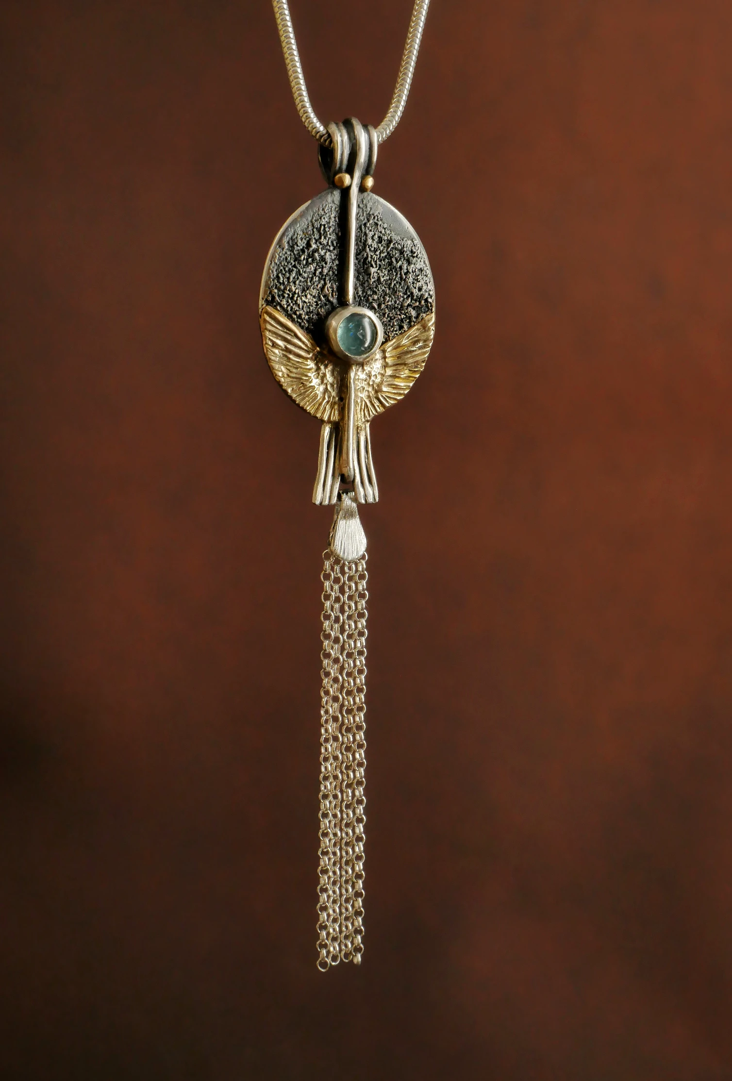 Pendentif orfèvre Eliz'art – œuf d'argent 950, ailes or 14k déployées, axe vertical et tourmaline bleue, création unique Bordeaux