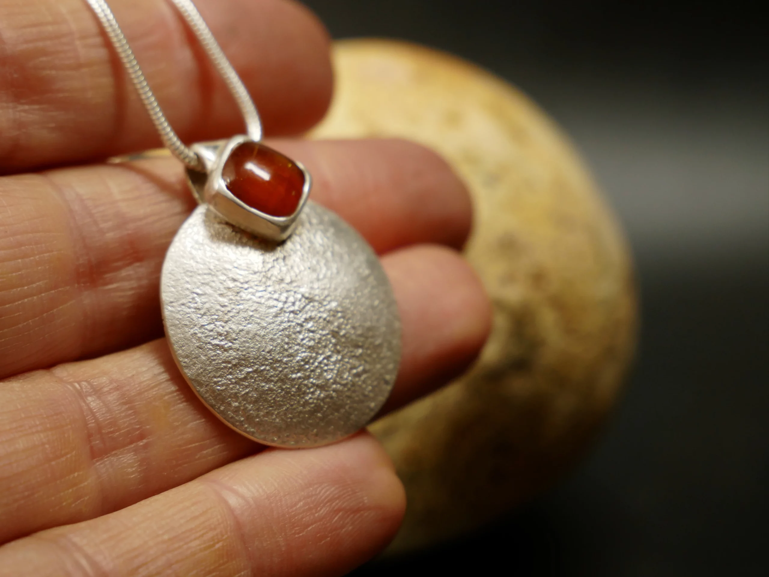 Pendentif en argent texturé, aspect lunaire, avec cyanite orange. Pièce unique faite main à Bordeaux par Eliz'art