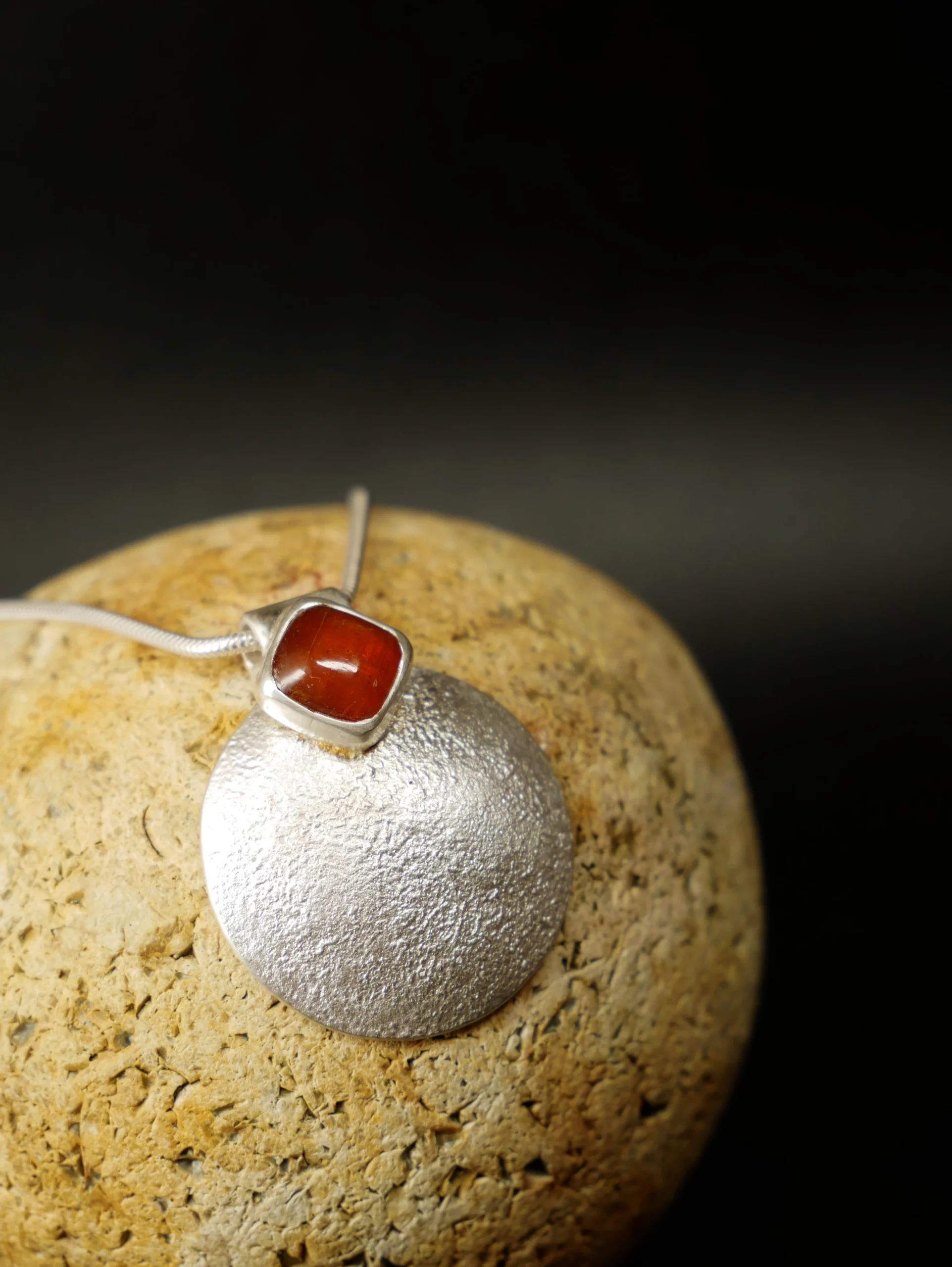 Pendentif en argent texturé, aspect lunaire, avec cyanite orange. Pièce unique faite main à Bordeaux par Elizart