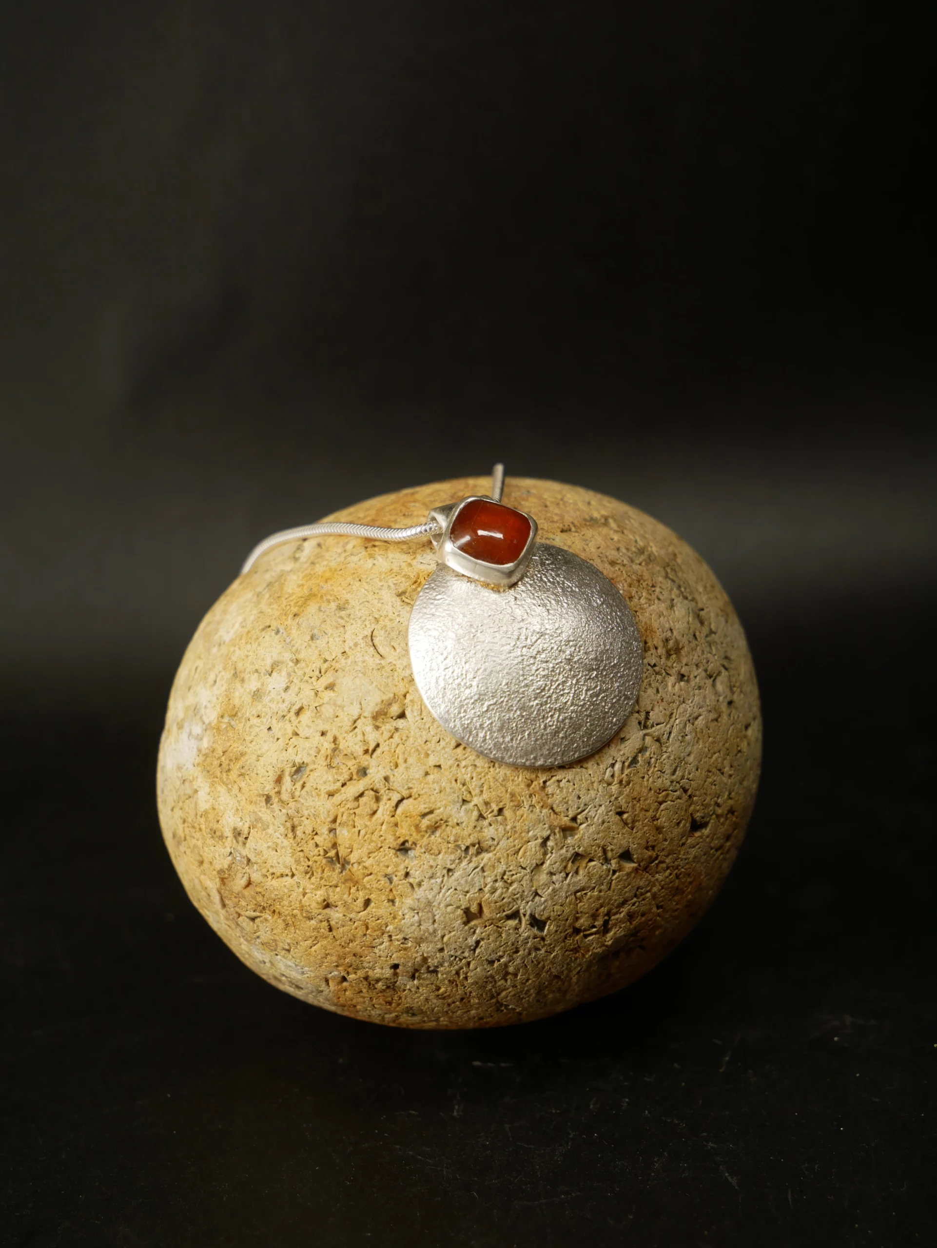 Pendentif en argent texturé, aspect lunaire, avec cyanite orange. Pièce unique faite main à Bordeaux par Elizart